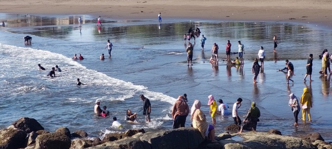 MASIH MANDI: Meski sudah ada papan larangan mandi di bibir pantai, masih ada saja pengunjung yang membandel. Mereka tetap bermain air mandi di Pantai Payangan.