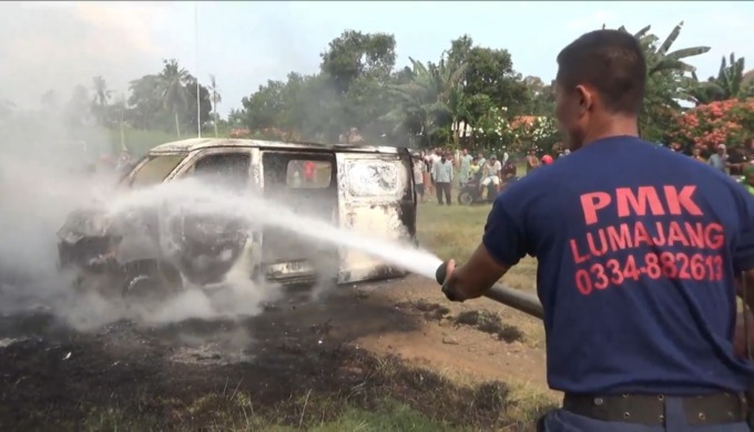 PADAM: Petugas pemadam kebakaran (damkar) Satpol PP Lumajang berupaya memadamkan minibus yang terbakar di lapangan Desa Curahpetung, Kecamatan Kedungjajang, kemarin.