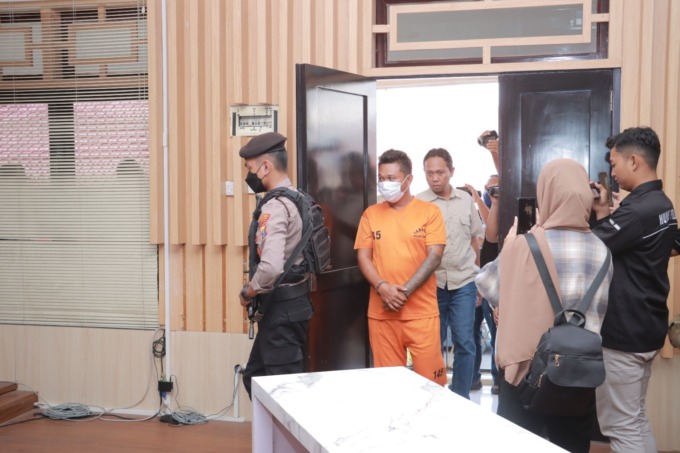 DIKAWAL: AA, 43, seorang kurir narkoba sudah memakai baju tahanan dan dikawal ketat oleh polisi di Polres Jember, kemarin (3/5).