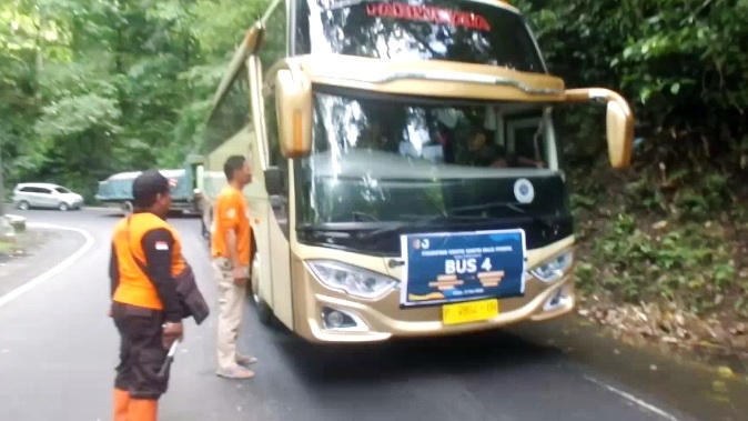 BERI PERINGATAN: Personel TRC BPBD Jember menghentikan bus penghalang mobil tim evakuasi ketika melintas di Gumitir. (Foto: Tangkapan Layar Video TRC BPBD Jember)