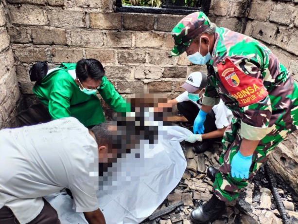 TERPANGGANG: Petugas mengevakuasi Katinah, nenek yang meninggal dunia bersamaan dengan api yang melalap rumahnya di Desa Kaliuling, Kecamatan Tempursasi, Lumajang, Rabu (10/5). (Cahyo untuk Rame)