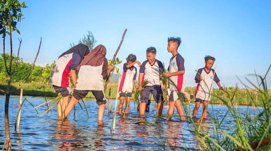 CEGAH ABRASI: Pelajar menanam mangrove di pesisir Pantai Cemara, Dusun Getem, Desa Mojomulyo, Kecamatan Puger, Jember. Kegiatan ini diikuti ratusan siswa serta anggota TNI/ Polri, serta masyarakat. (SMPN 3 Puger untuk Radar Jember)