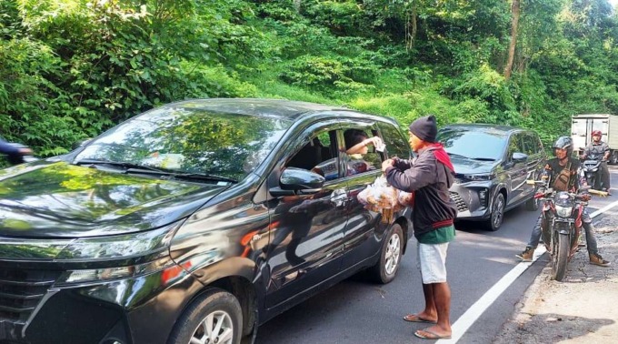 PELUANG BERDAGANG: Salah seorang pengasong menjajakan dagangannya di tengah kemacetan jalur Gumitir. Hari ini (19/5), polisi menutup total jalur penghubung Jember-Banyuwangi itu, karena ada evakuasi truk dari dalam jurang.(Jumai/Radar Jember)