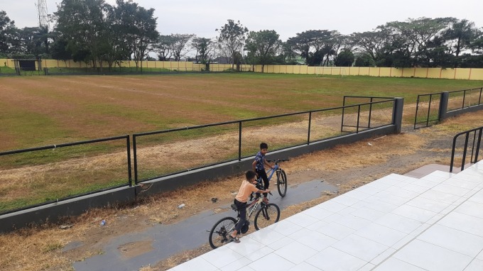 TEMPAT BERMAIN: Anak-anak yang leluasa bersepeda di Stadion Magenda. Stadion terbesar milik Bondowoso itu rumputnya mulai menguning.
