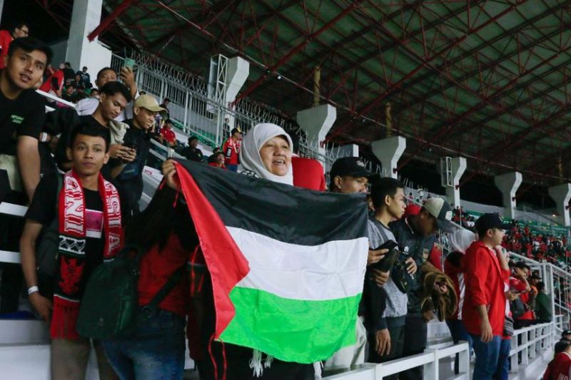 Wakil Ketua DPRD Surabaya Reni Astuti membentangkan bendera Palestina dari tribun Stadion Gelora Bung Tomo (GBT) saat pertandaningan Timnas Indonesia melawan Palestina pada Rabu (14/6/malam.