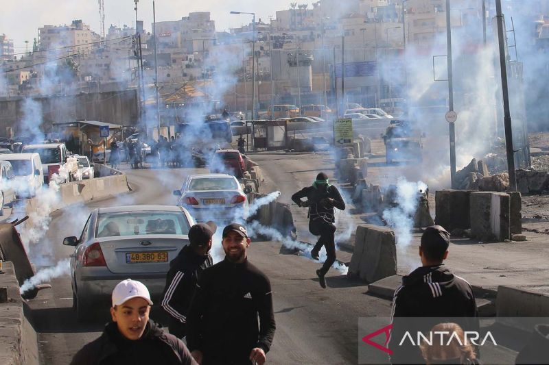 Arsip - Pengunjuk rasa Palestina berlarian untuk berlindung dari tabung gas air mata yang ditembakkan pasukan keamanan Israel dalam bentrokan di pos pemeriksaan Qalandia di dekat Kota Ramallah di Tepi Barat (27/12/2022). ANTARA.