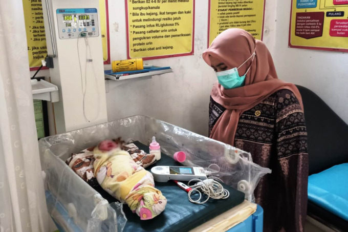 DALAM PERAWATAN: Tenaga medis Puskesmas Karangduren memeriksa kondisi bayi laki-laki yang ditemukan warga di teras rumah. (Polsek Balung untuk Radar Jember)