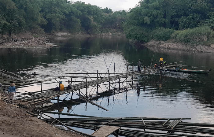 GOTONG ROYONG: Sejumlah warga Desa Sidolaju, Widodaren, Ngawi, membangun jembatan darurat menggunakan bahan bambu kemarin. (ASEP SYAEFUL BACHRI/JAWA POS RADAR NGAWI)