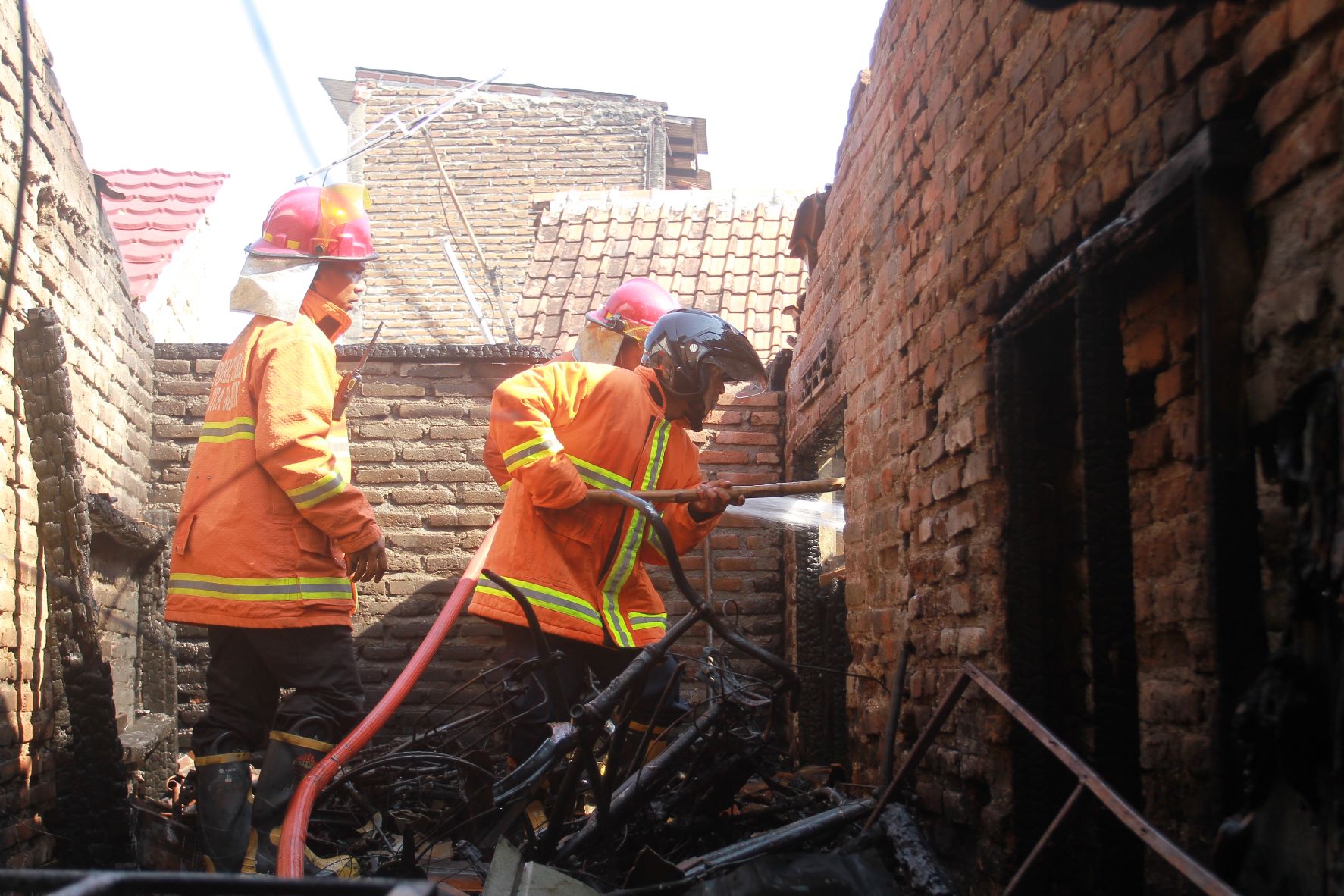 KEBAKARAN: Petugas Satpol PP dan Damkar Kota Madiun melakukan pembasahan di dapur rumah milik Sri Asmah di Jalan Indragiri Gang I yang terbakar kemarin (18/7).&nbsp;(BAGAS BIMANTARA/RADAR MADIUN)