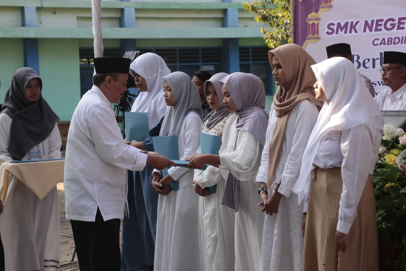 BERBAGI: Kepala SMKN 2 Kota Madiun Taridjo saat menyerahkan santunan kepada siswa yang kurang mampu. (ABRIANTO WIBOWO/RADAR MADIUN)