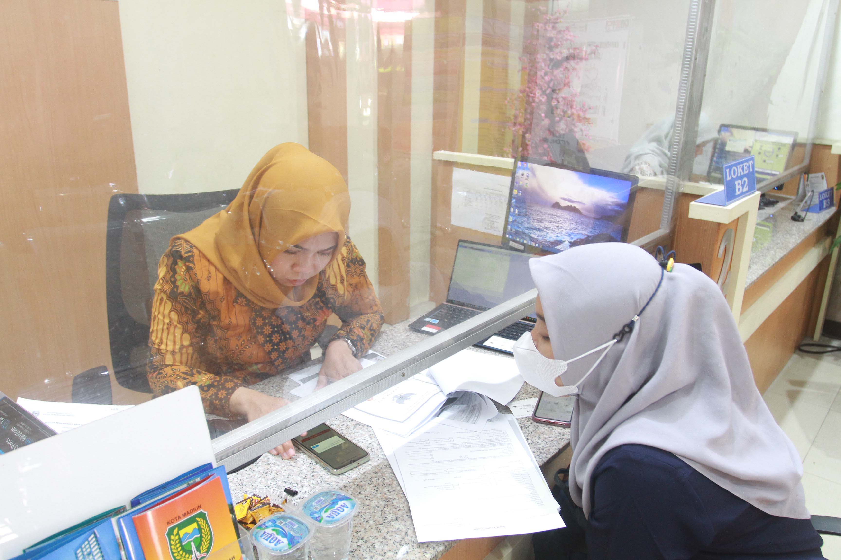 TAAT PAJAK: Seorang warga ketika melakukan pembayaran pajak di kantor pelayanan Bapenda Kota Madiun kemarin (3/8). (BAGAS BIMANTARA/RADAR MADIUN)