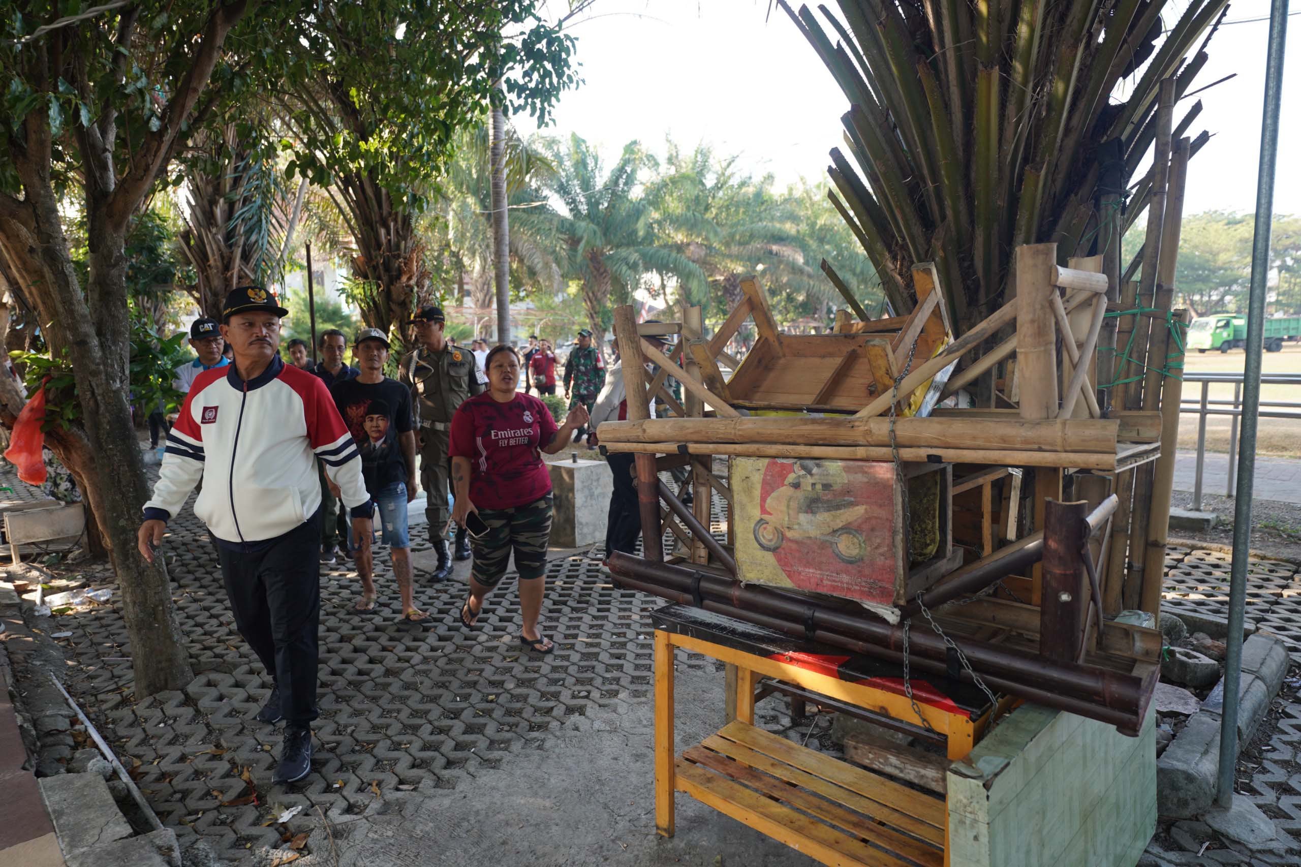 BAKAL DITATA: Petugas satpol pp dengan dibantu anggota linmas menertibkan lapak pedagang yang berada di sisi utara Lapangan Gulun kemarin (11/8). (DISKOMINFO UNTUK RADAR MADIUN)