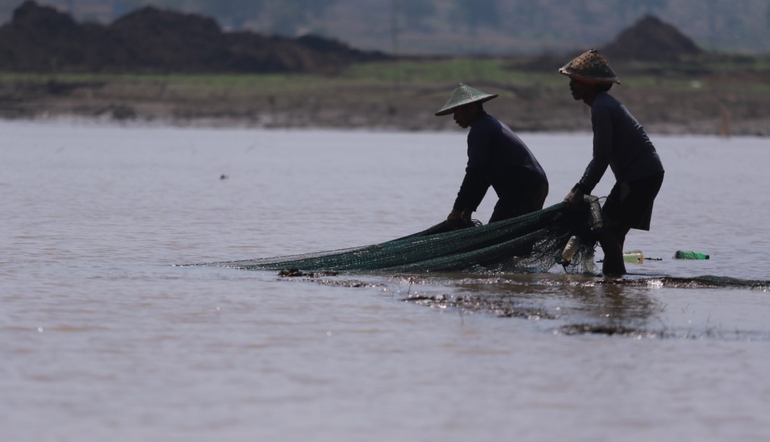 EFEK KEMARAU: Warga sekitar menjaring ikan dari Waduk Dawuhan yang airnya menyusut. (R. BAGUS RAHADI/RADAR MADIUN)