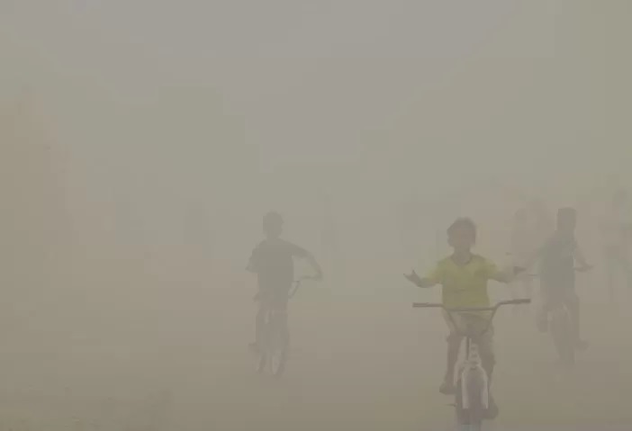 Anak-anak melintasi jalan dengan kondisi kepungan kabut asap sekitar lokasi kebakaran hutan dan lahan (karhutla) di Kota Banjarbaru, Kalimantan Selatan, Senin (14/8). (Tumpal Andani Aritonang/Antara)