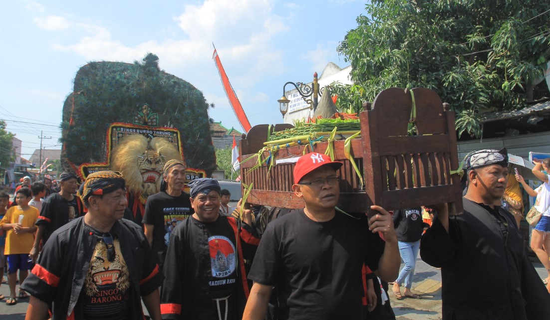 KIRAB: Dengan diiringi kesenian reog, tokoh masyarakat adat Nambangan Lor memikul tumpeng yang selanjutnya dilarung di Kali Madiun kemarin (18/8).&nbsp;(BAGAS BIMANTARA/RADAR MADIUN)