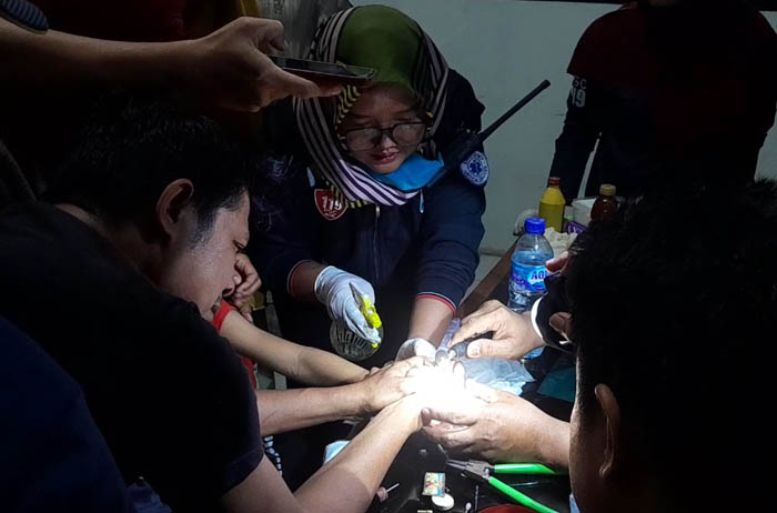 SAKITNYA MINTA AMPUN: Petugas damkar dan tim medis berjuang melepas besi ikat pinggang yang menancap di jari tengah gadis 10 tahun kemarin. (ASEP SYAEFUL BACHRI/JAWA POS RADAR NGAWI)