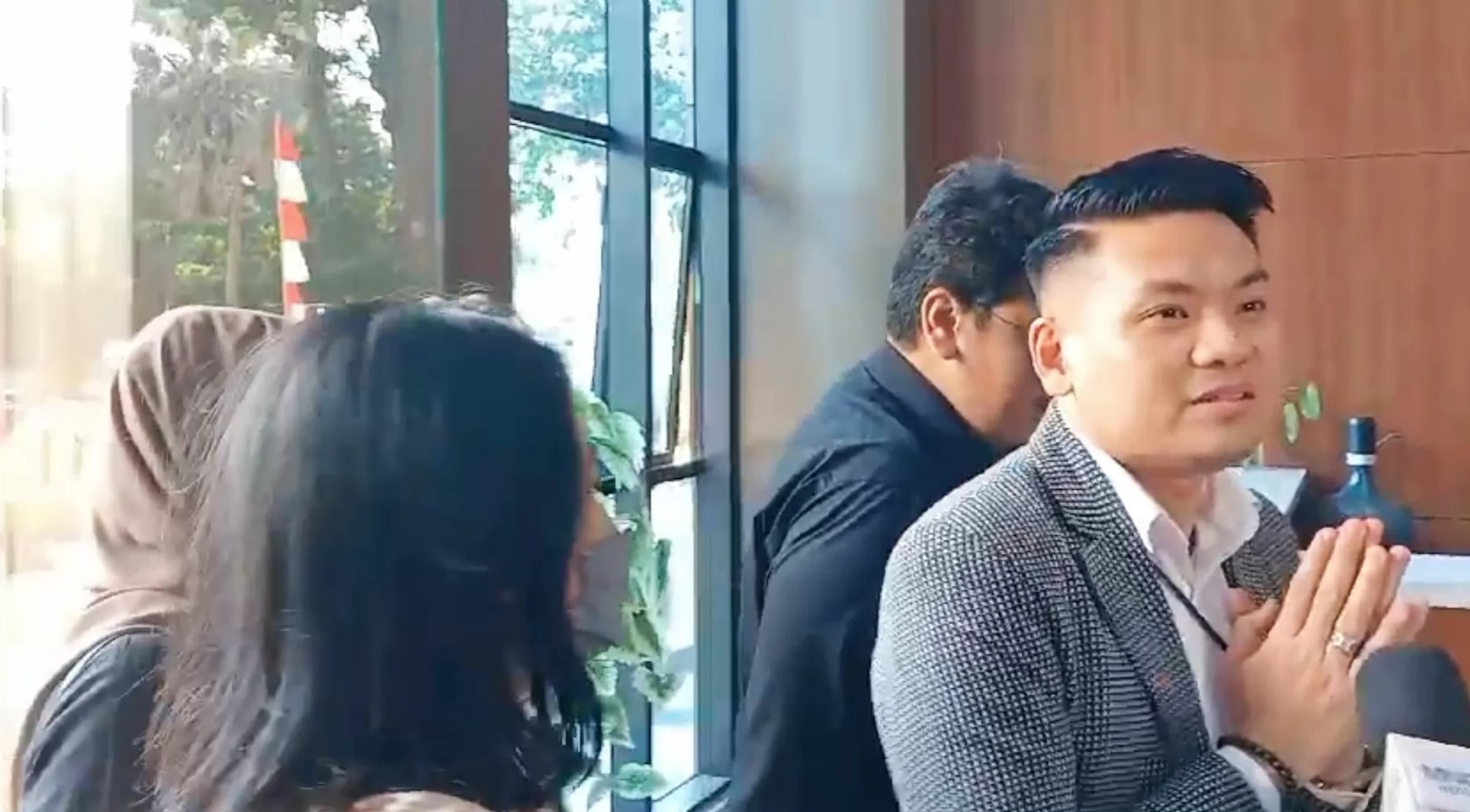 MENGHINDAR: Oklin Fia berlindung di balik tim pengacara di sela menghadiri pemeriksaan polisi. (JAWAPOS.COM)