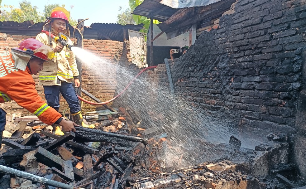 HANGUS: Petugas pemadam kebakaran (damkar) melakukan proses pendinginan di lahan yang terbakar di Jalan Sri Wibowo, Sukosari kemarin (1/9).&nbsp;(HENGKY RISTANTO/RADAR MADIUN)