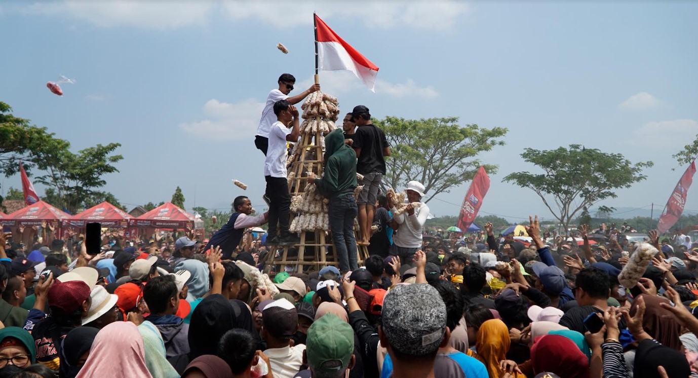 DISERBU: Ratusan warga berebut gunungan raksasa kue manco pada puncak Festival Manco Madiun di Desa Tambakmas, Kebonsari, Kabupaten Madiun, kemarin (3/9). (R. BAGUS RAHADI/RADAR CARUBAN)