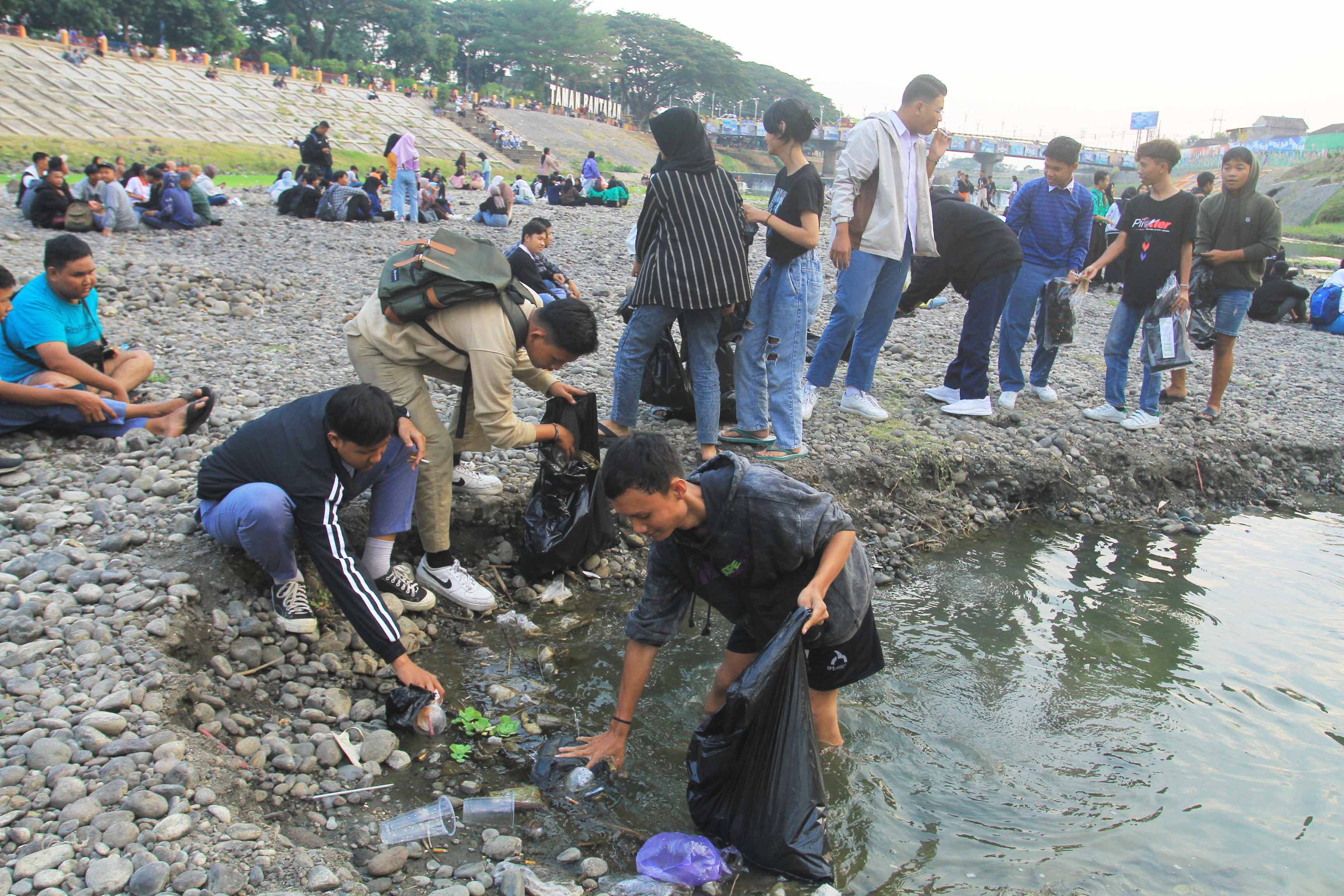 BERSIH-BERSIH: Para anak muda yang tergabung dalam Gerakan Positif membersihkan sampah di tengah Kali Madiun kemarin (5/9).&nbsp;(BAGAS BIMANTARA/RADAR MADIUN)&nbsp;