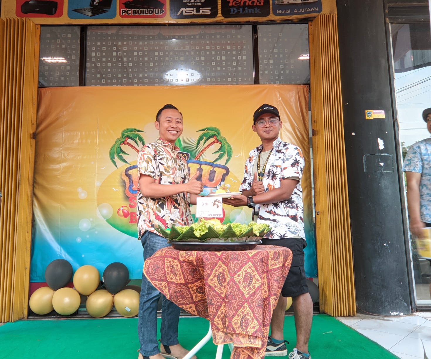 SIMBOLIS:&nbsp;Andi Cahyoko potong tumpeng didampingi Ketut, manager B2B Maju Hardware. (SUCI OKTA/RADAR PACITAN)