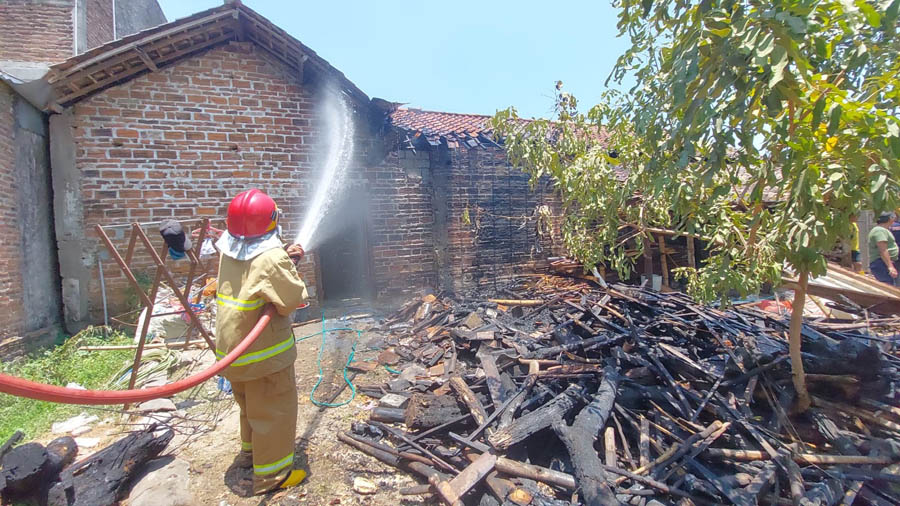 LUDES TERBAKAR : Petugas pemadam kebakaran memadamkan api yang membakar tumpukan kayu di belakang rumah Sukamto, warga Desa Sidorejo, Kebonsari Madiun, Senin (26/9) siang.
