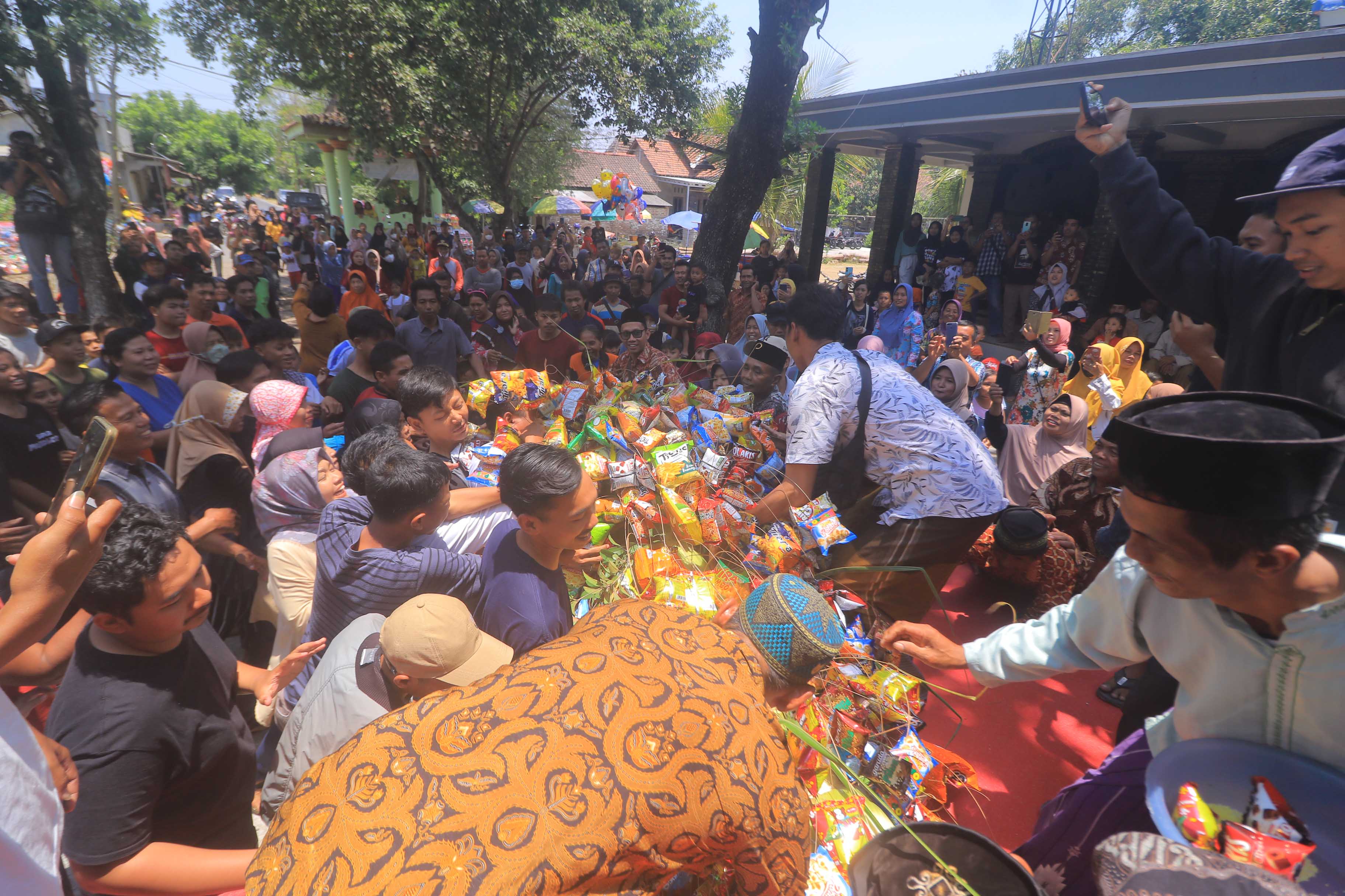 NGURI-URI: Warga Desa Kedondong, Kebonsari antusias berebut uang koin dan gunungan jajan dalam rangka peringatan Maulid Nabi Muhammad SAW, kemarin (28/9).&nbsp;(BAGUS RAHADI/JAWA POS RADAR CARUBAN)