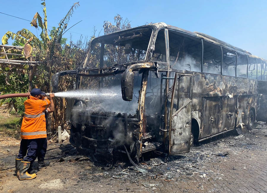 GOSONG : Petugas pemadam kebakaran melakukan pembasahan usai berhasil memadamkan api yang membakar bus pariwisata di tepi jalan Desa Widodaren, Ngawi. (ASEP SAEFUL BACHRI/JAWA POS RADAR NGAWI)