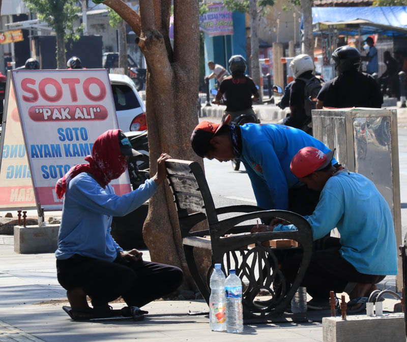 FASILITAS PUBLIK: Pekerja memasang kursi taman di pedestrian Ursum. (SUGENG DWI N/JAWA POS RADAR PONOROGO)