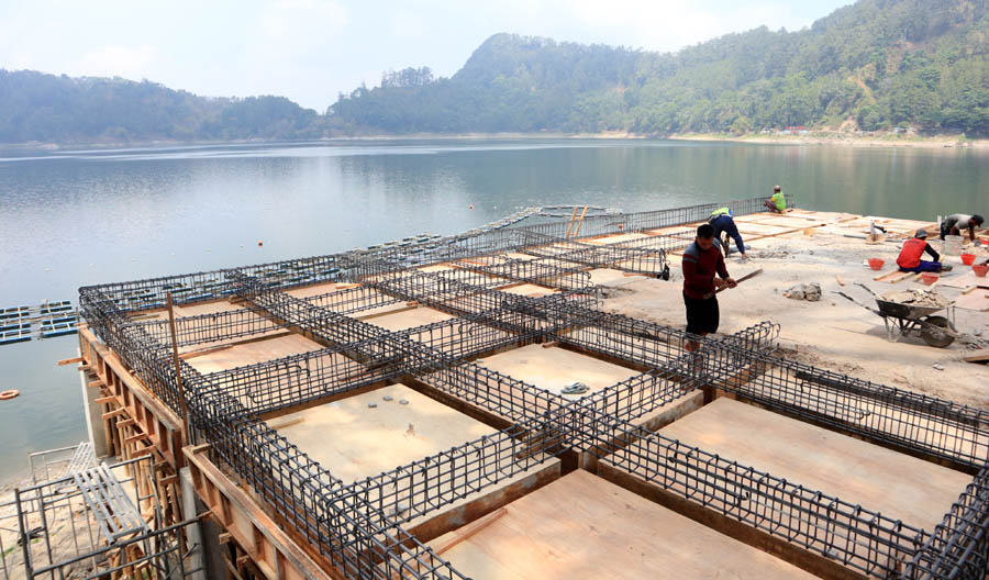 PROGRESIF: Pekerja mengebut pembangunan tribun penonton water fountain Telaga Ngebel sebelum diresmikan November. (SUGENG DWI N. /JAWA POS RADAR PONOROGO)
