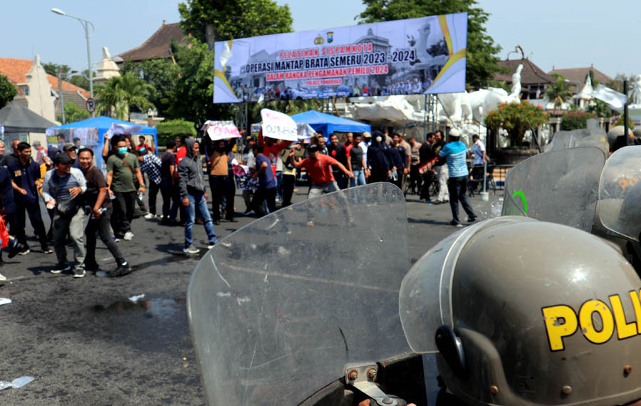 SIAGA: Kelompok massa melempari petugas dalam simulasi pengamanan Pemilu yang digelar di Alun-alun Ponorogo, kemarin (17/10). (SUGENG DWI N./JAWA POS RADAR PONOROGO)