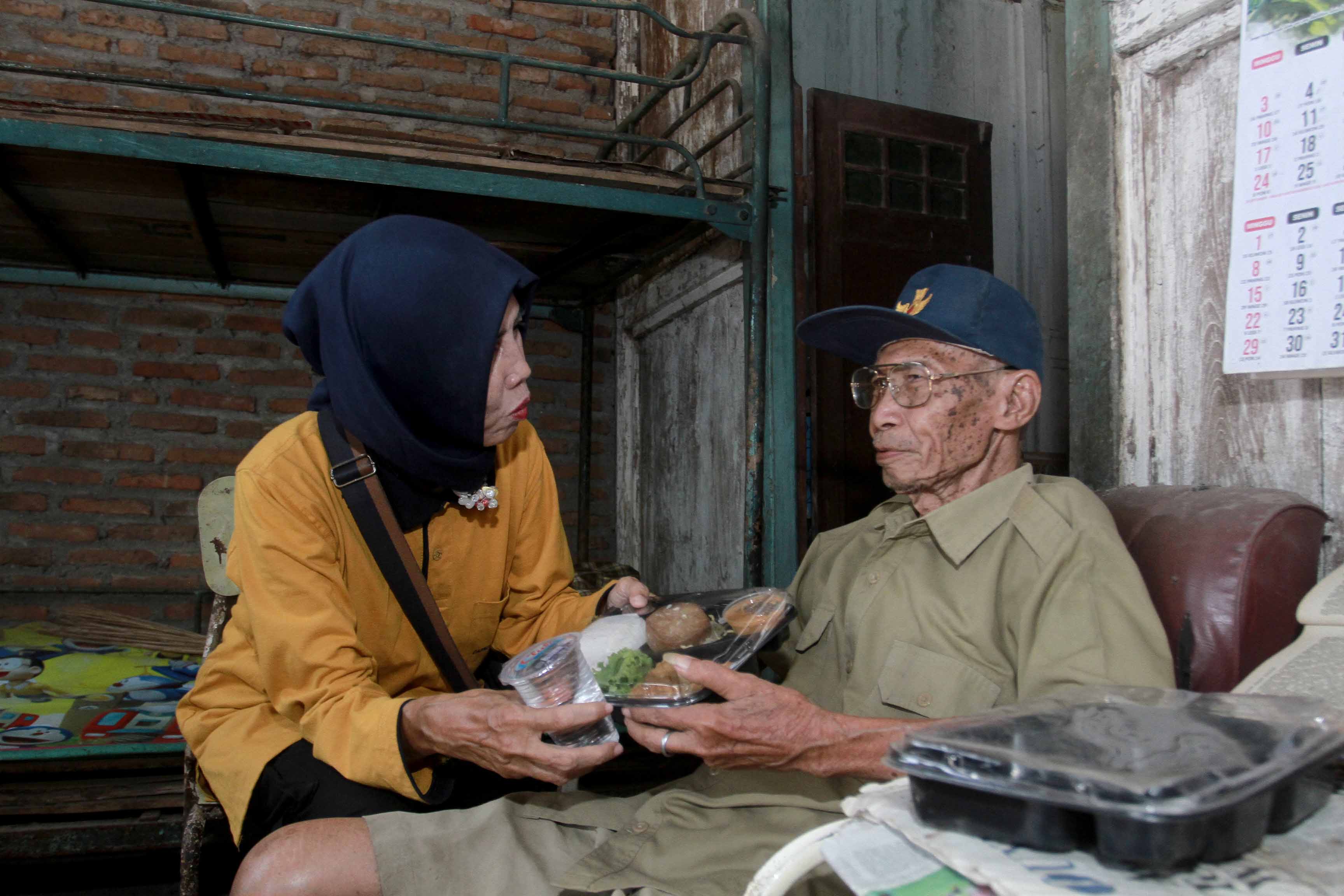 BANTUAN: Seorang pekerja sosial masyarakat (PSM) memberikan bantuan makan kepada Soetomo yang termasuk lansia tunggal di Kelurahan Pangongangan kemarin (24/10). (BAGAS BIMANTARA/RADAR MADIUN)
