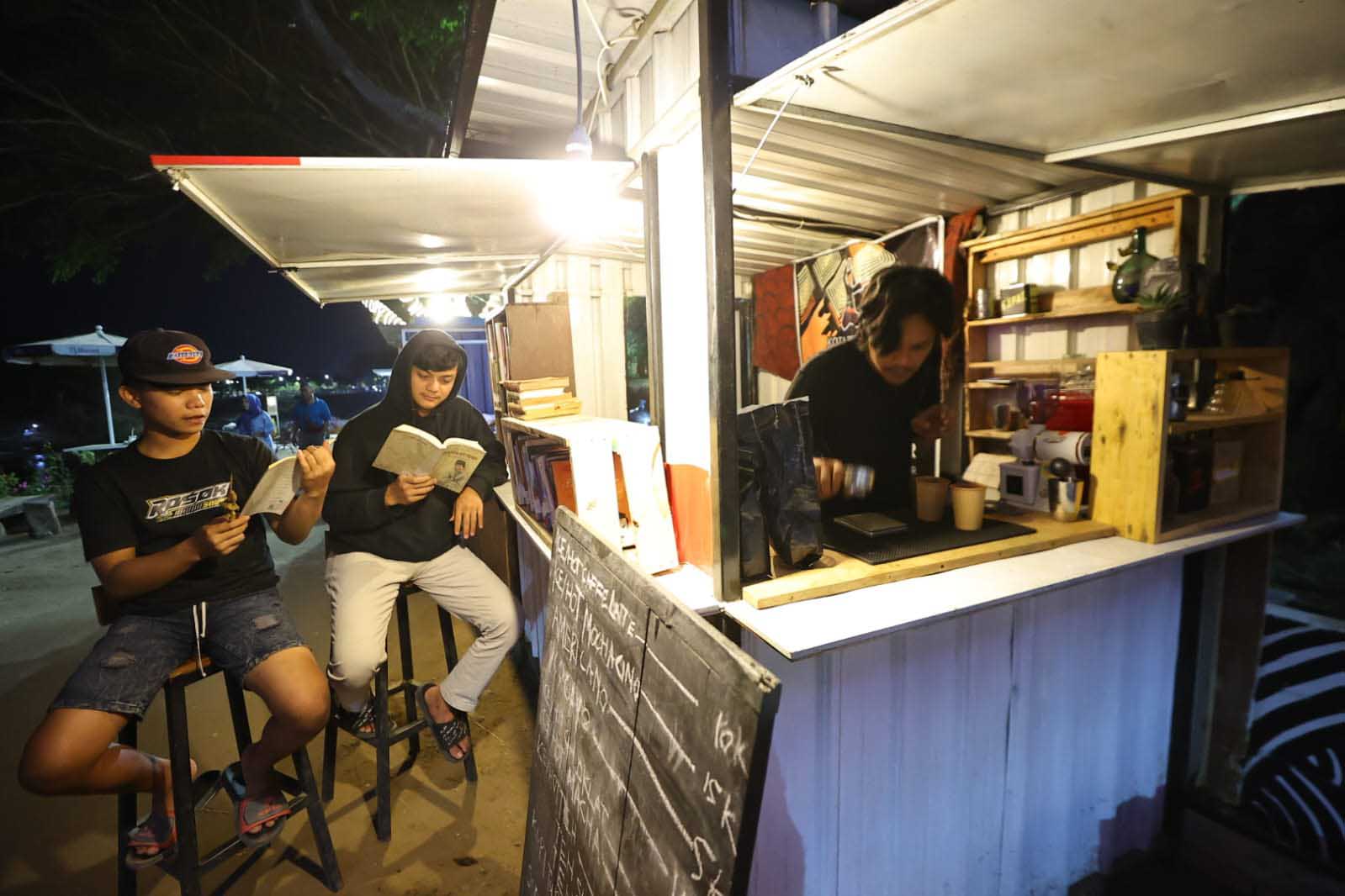 UNIK: Warung Literasi Bantaran Kali Madiun yang memadukan tempat ngopi dengan ruang membaca.&nbsp;(WS HENDRO UNTUK RADAR MADIUN)&nbsp;