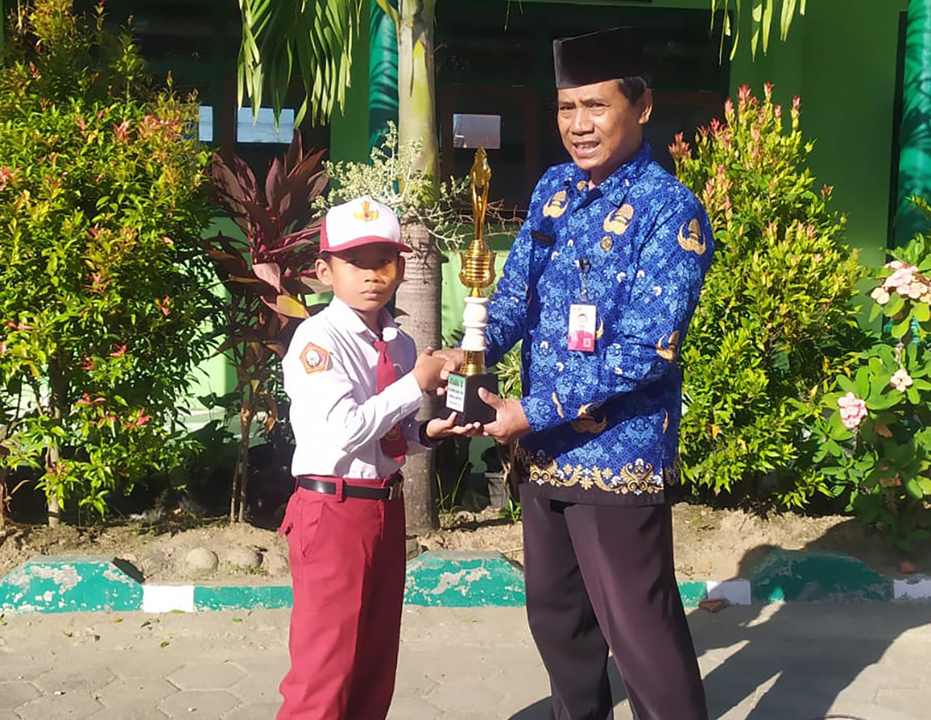 BANGGA : Kepala SDN Tanjungrejo 03 Purwadi sedang berfoto bersama juara Olimpiade PAI Mohammad Faiz Abdul Fattah.&nbsp;(SDN TANJUNGREJO 03 FOR RADAR CARUBAN)