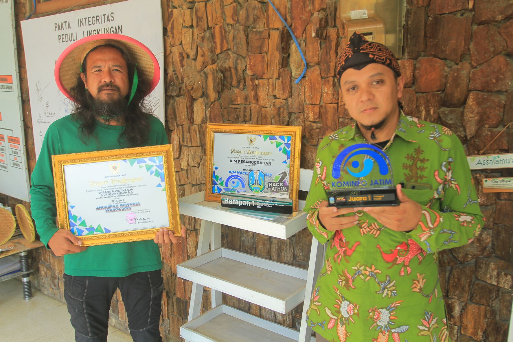 KREATIF: Wisang R. Wijaya (kanan) dan Gentur Kusuma menunjukkan dua penghargaan yang mereka terima dari Dinas Kominfo Jatim, Minggu (5/11). (BAGAS BIMANTARA/RADAR MADIUN)