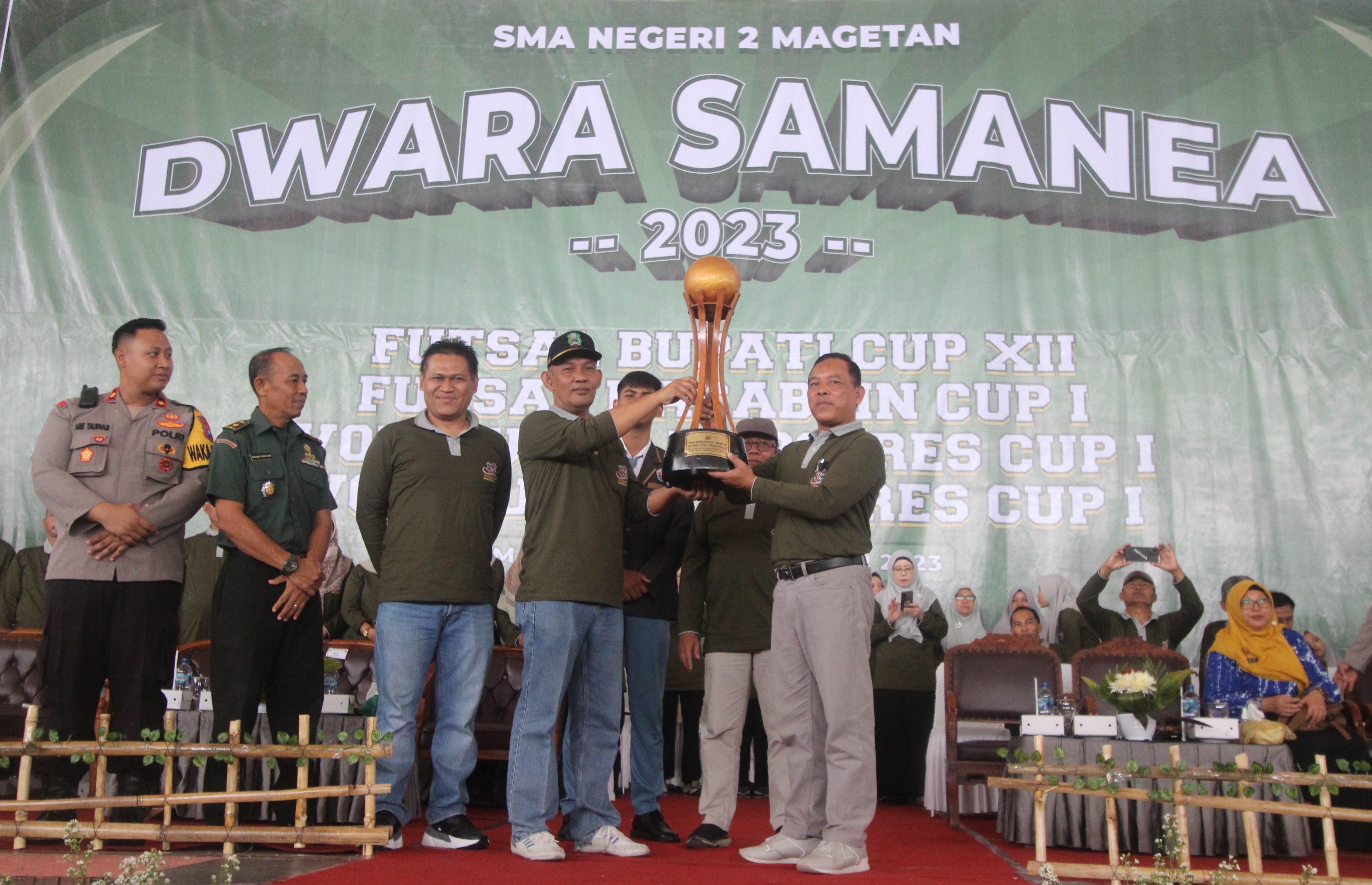PEMBUKAAN KOMPETISI: Pj Bupati Magetan Hergunadi bersama Kepala Sekolah SMAN 2 Magetan Suroso mengangkat piala bergilir Bupati Cup ke XII di Gor Ki Mageti, Kamis (9/11). (AJI PUTRA/RADAR MAGETAN)