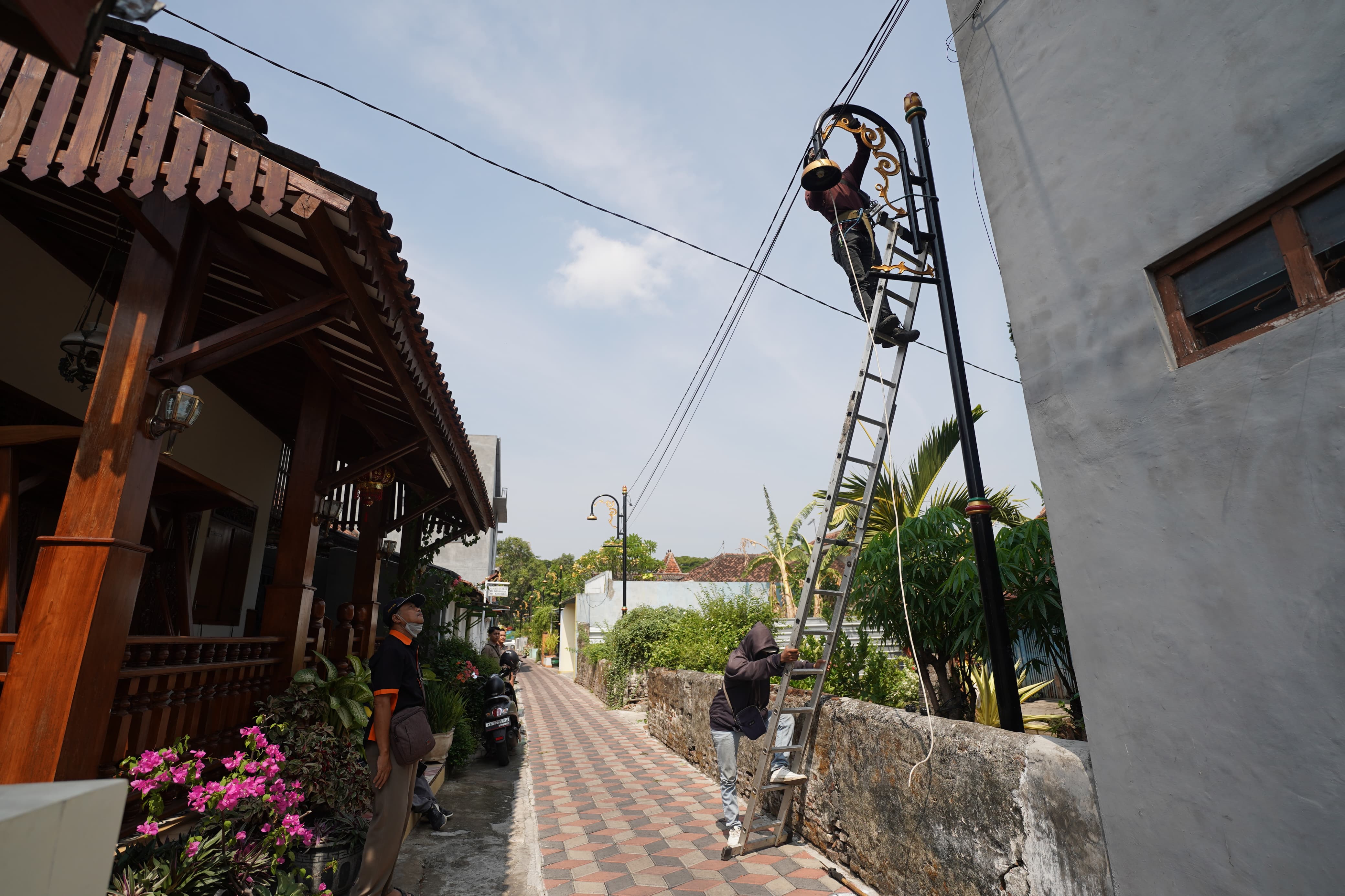 TERANG: Pekerja tengah memasang instalasi kelistrikan proyek lampunisasi di jalan-jalan lingkungan di Kota Madiun. (DISKOMINFO KOTA MADIUN)