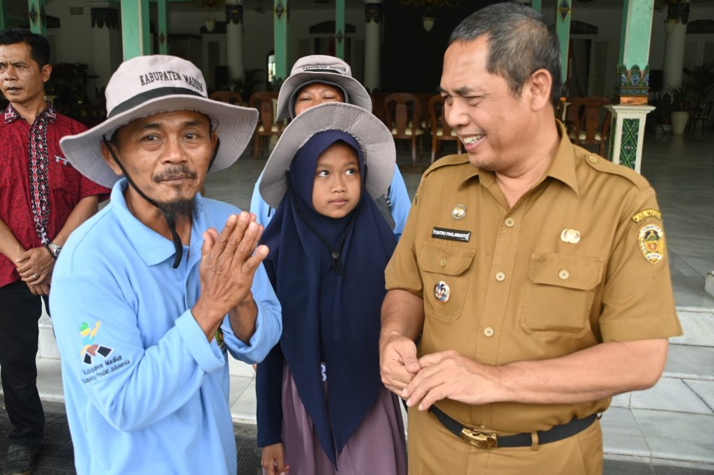 BAHAGIA CAMPUR HARU: Triyono beserta anak istri dilepas PJ Bupati Madiun Tontro Pahlawanto untuk mengikuti program transmigrasi ke Kabupaten Bengkulu Selatan, Selasa (21/11). (DISKOMINFO)