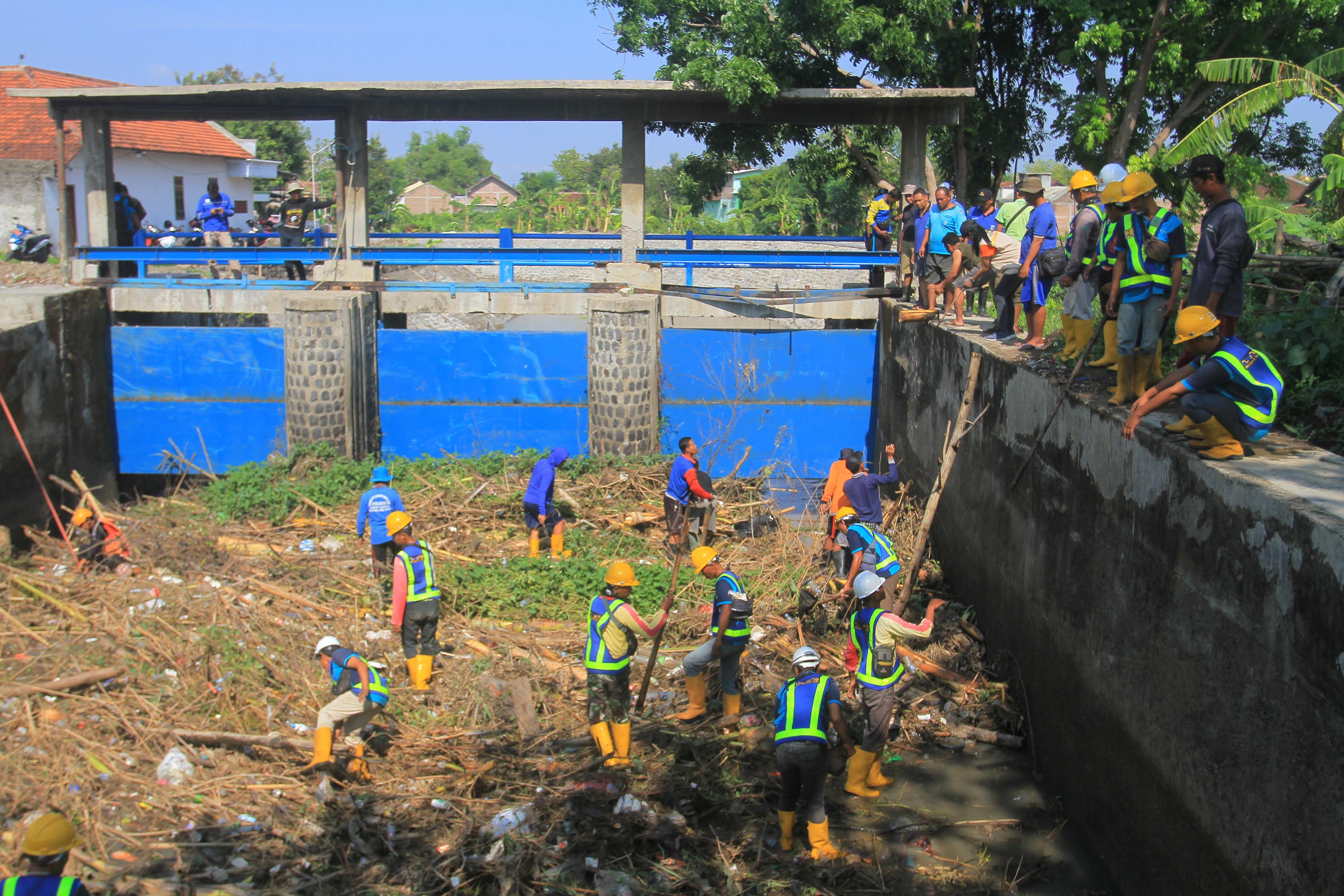 MITIGASI: Sejumlah petugas dari berbagai pihak terkait membersihkan sampah di Dam Sono, Kamis (30/11). (BAGAS BIMANTARA/RADAR MADIUN)