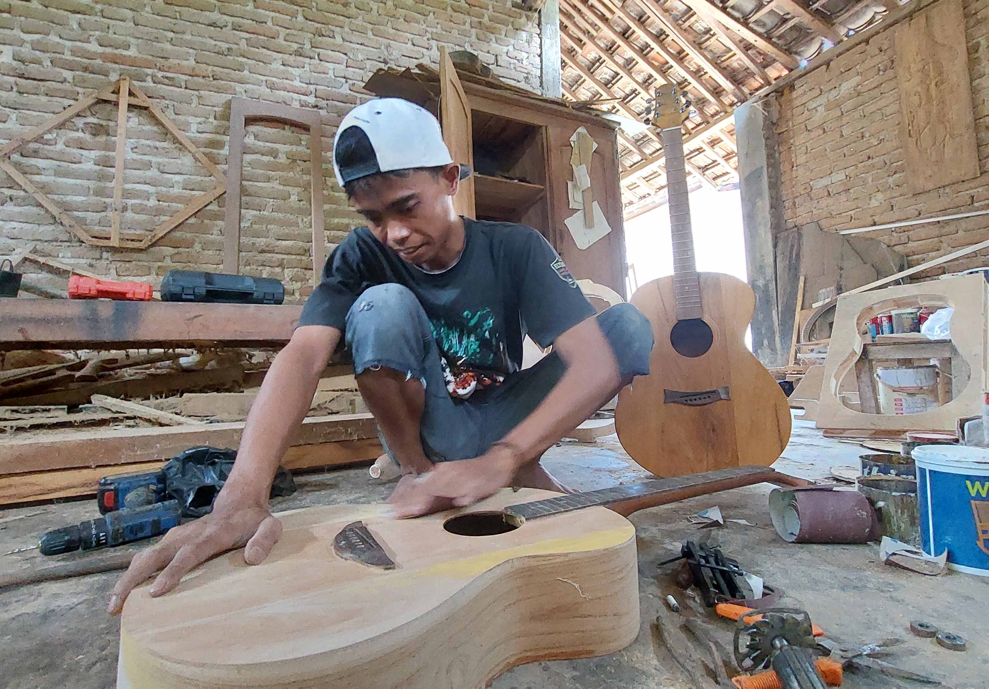 TELATEN: Slamet saat proses membuat gitar di bengkelnya Desa Pucanganom, Kebonsari. (DIAN RAHAYU/RADAR CARUBAN)