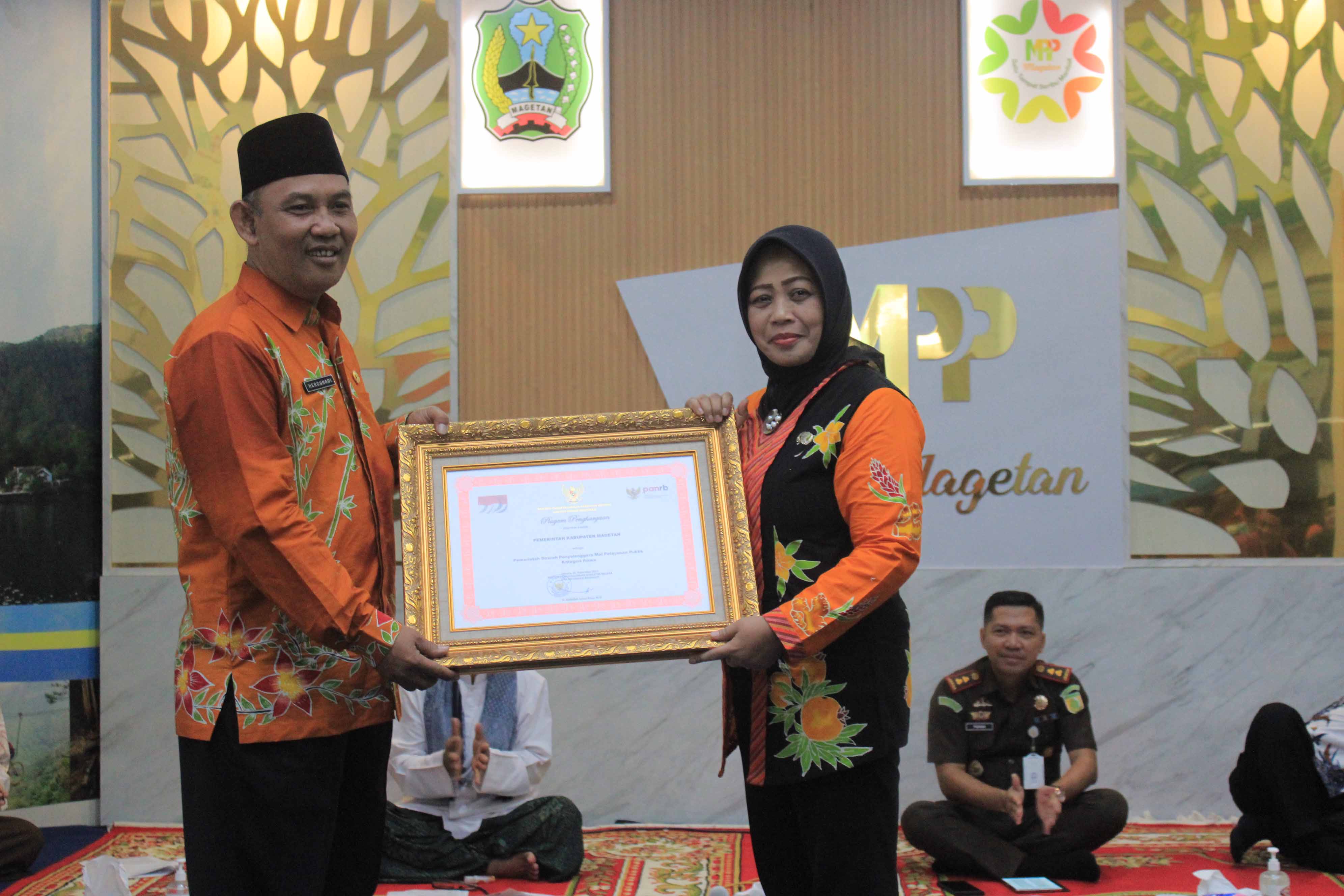 BERGENGSI: Pj Bupati Magetan Hergunadi menyerahkan penghargaan pelayanan Prima untuk MPP kepada Kepala DPMPTSP Magetan Sunarti Condrowati, kemarin (15/12).&nbsp;(AJI PUTRA/RADAR MAGETAN)