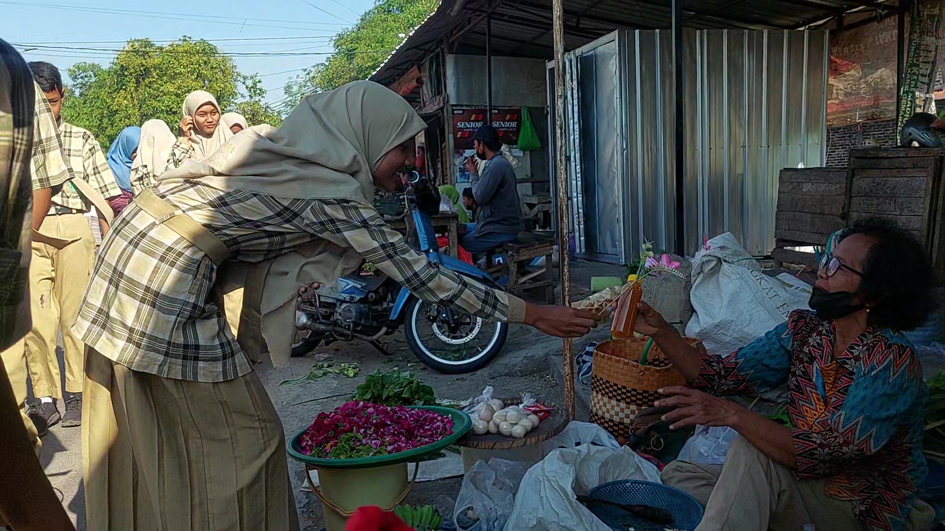 TANDA KASIH: Dalam rangka Hari Ibu, siswa bagikan bunga artifisial dan jamu ke pedagang Pasar Barakan, Desa Dempelan, Kecamatan/Kabupaten Madiun. (DIAN RAHAYU/RADAR CARUBAN)