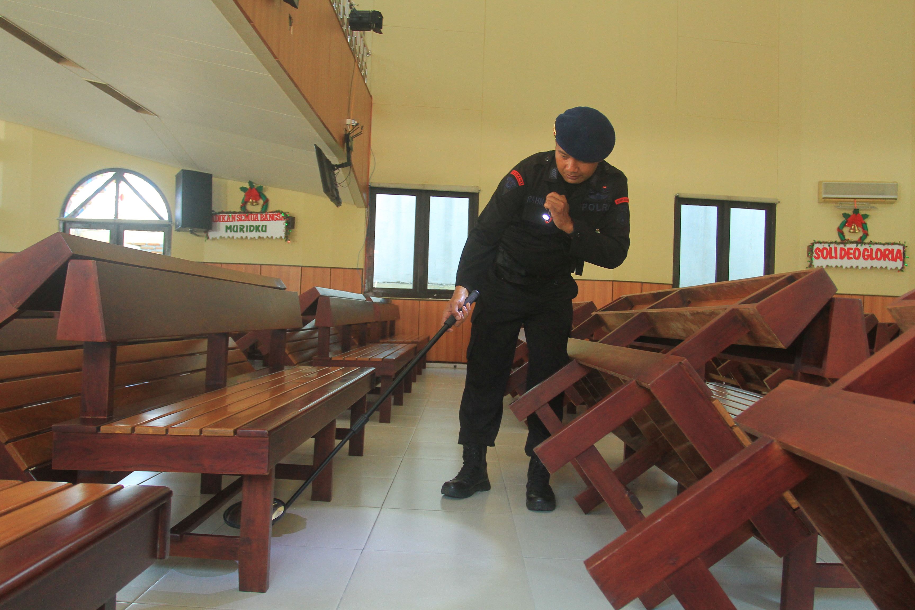 PASTIKAN AMAN: Petugas gabungan dari Polres Madiun Kota dan tim penjinak bom Batalyon C Pelopor Satbrimob Polda Jatim melakukan sterilisasi gereja. (BAGAS BIMANTARA/RADAR MADIUN)