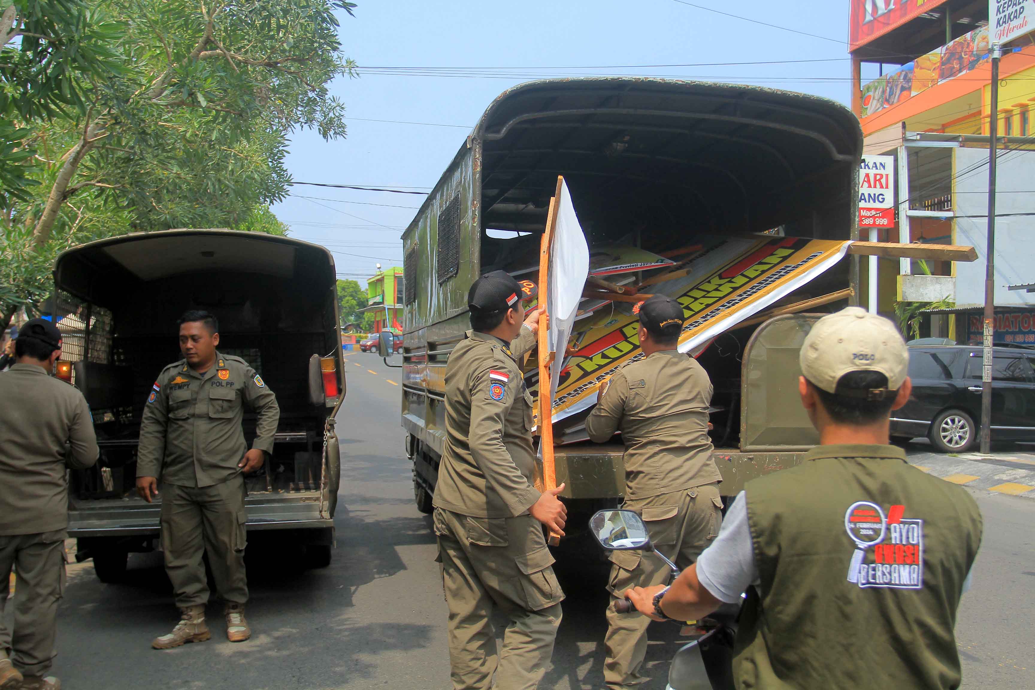 DIBREDEL: Petugas Satpol PP dan Bawaslu Kota Madiun menertibkan APK yang melanggar aturan di wilayah Kecamatan Manguharjo kemarin (2/12). (BAGAS BIMANTARA/RADAR MADIUN)