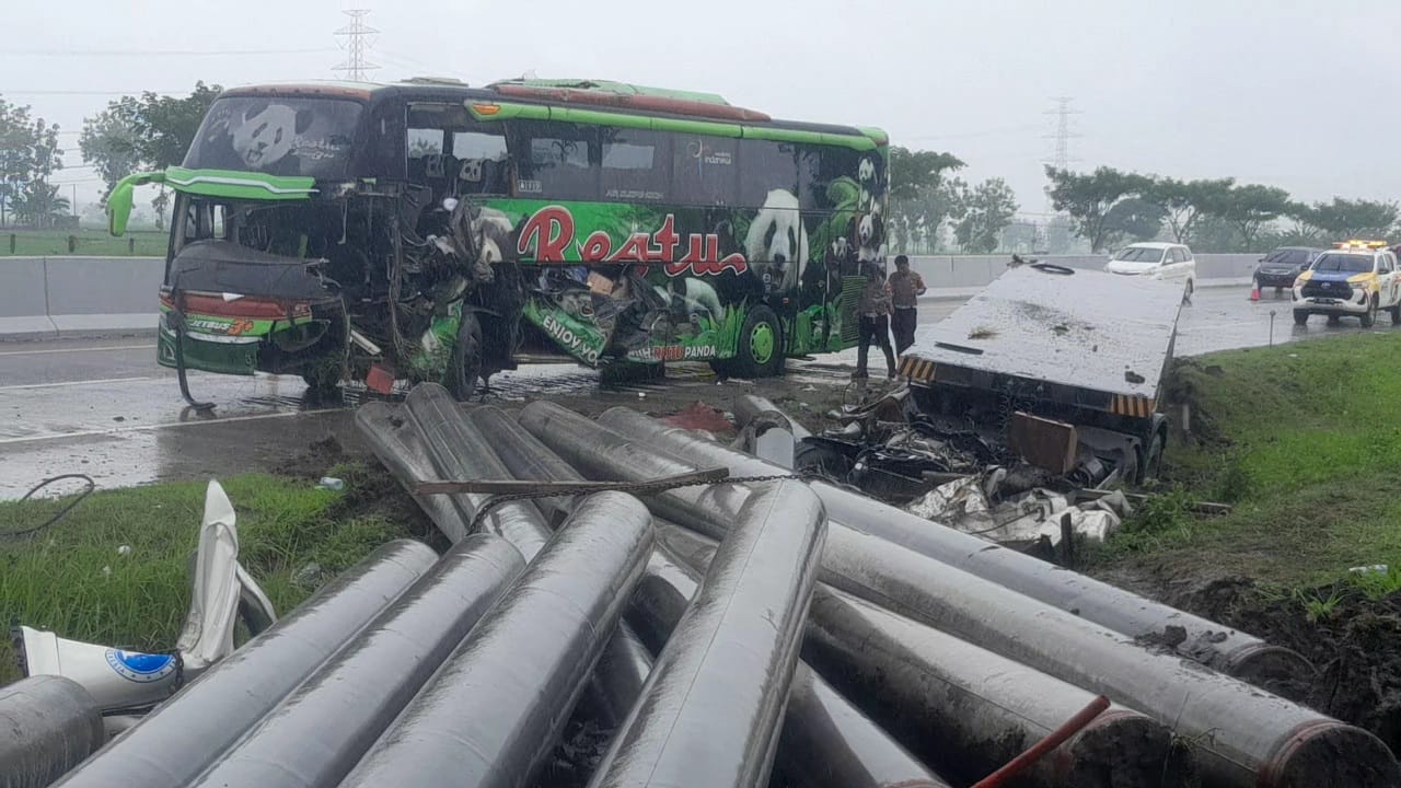 TUMPAH RUAH: Muatan tiang pancang yang dibawa truk trailer tumpah usai ditabrak bus pariwisata Restu, di Ngawi, Rabu (3/1) pagi. (ASEP SYAEFUL/RADAR NGAWI)
