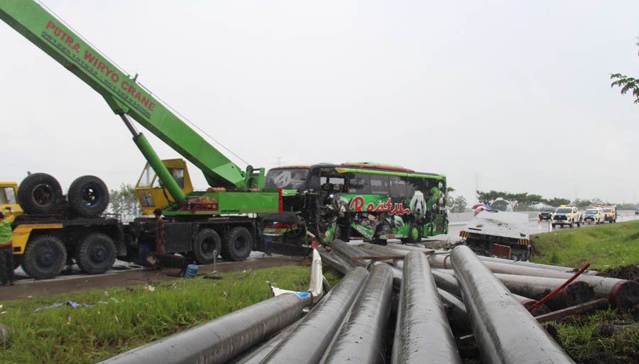 PETAKA DINI HARI: Alat berat mengevakuasi paku bumi di TKP kecelakaan bus Restu dengan truk trailer kemarin. (ASEP SYAEFUL BACHRI/JAWA POS RADAR NGAWI)