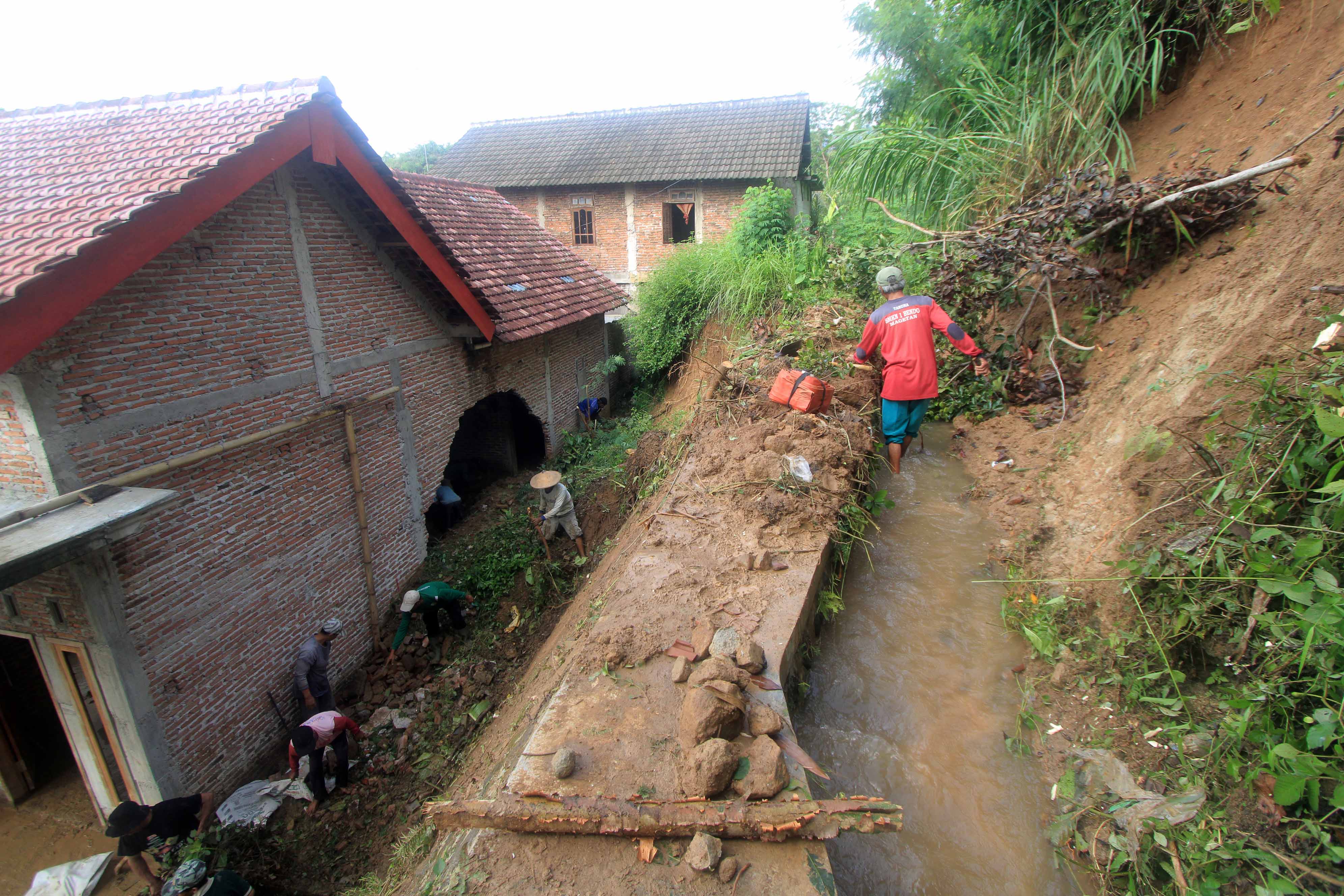 RUSAK PARAH: Longsor menjebol dinding rumah warga di Desa Sambirobyong, Kecamatan Sidorejo, Kamis (4/1) lalu. Kemarin (5/1), warga dibantu aparat melakukan kerja bakti. (AJI PUTRA/RADAR MAGETAN)