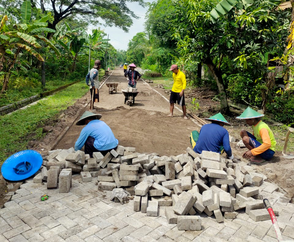 TERSELESAIKAN: Para pekerja saat pemasangan paving jalan yang berlokasi di RT 8 sampai RT 10. (PEMDES TAPELAN)