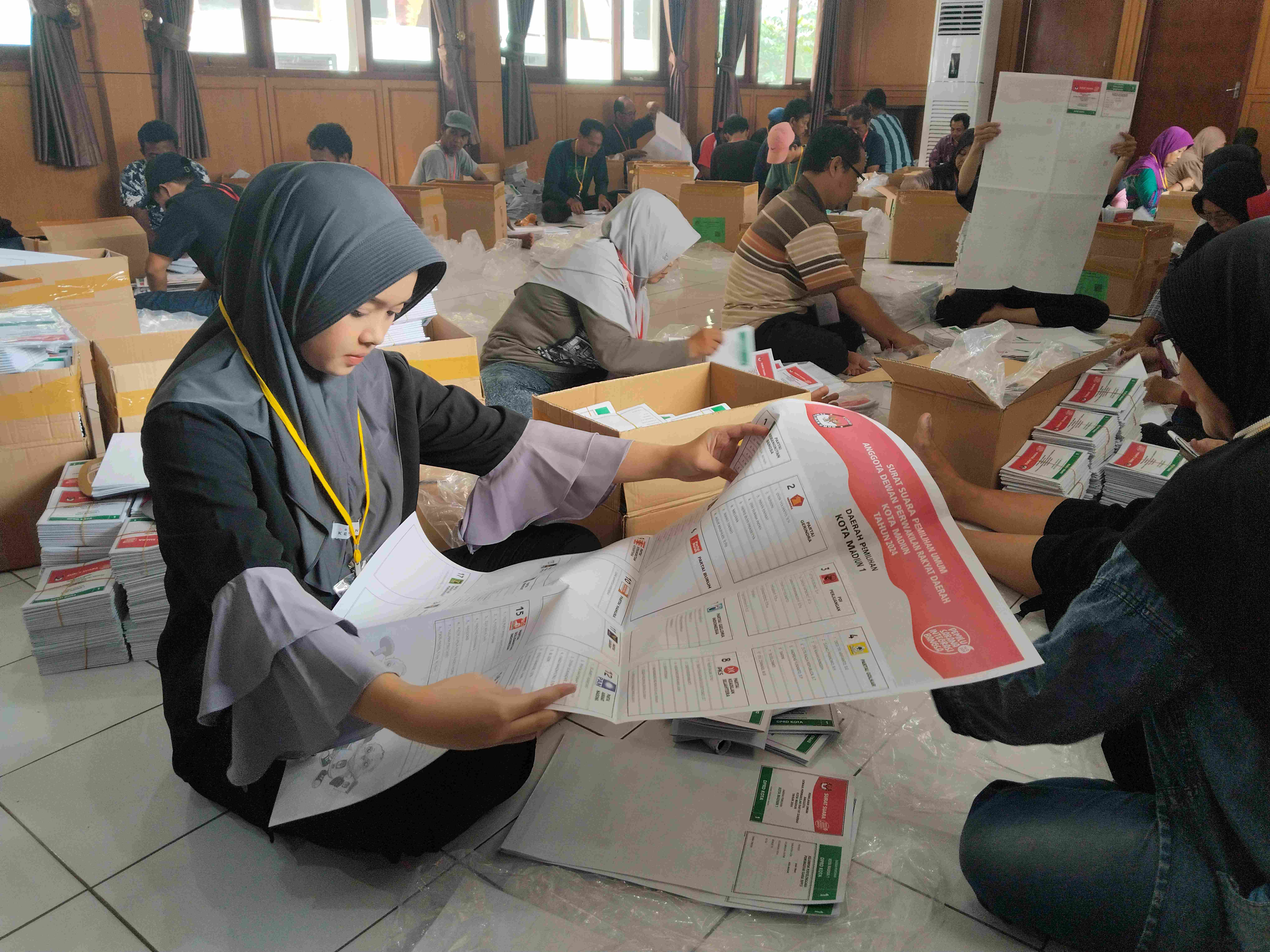LOGISTIK PEMILU: Petugas menyortir dan melipat ratusan ribu lembar surat suara untuk Pileg DPRD Kota Madiun di kantor KPU setempat kemarin (7/1). (BAGAS BIMANTARA/RADAR MADIUN)