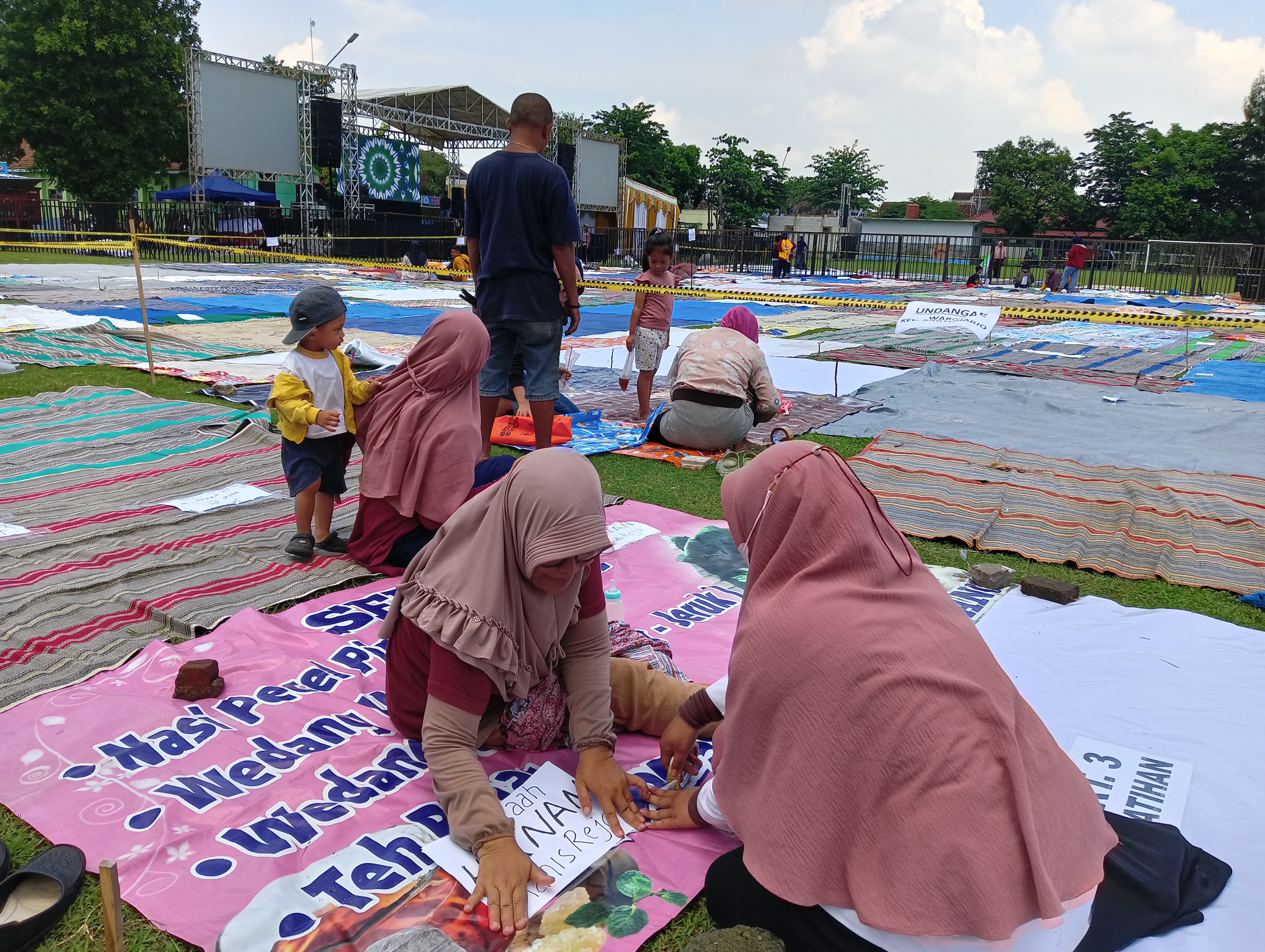 BOOKING TEMPAT: Jemaah ST Nyell menggelar tikar untuk pengajian Gus Iqdam di Lapangan Rejomulyo, Kota Madiun, Selasa (9/1) malam. (ERLITA/RADAR MADIUN)